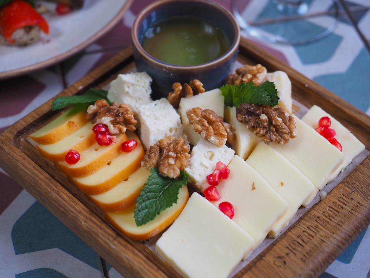 services-02 Delicious assortment of cheeses, walnuts, and pomegranate seeds on a wooden tray.