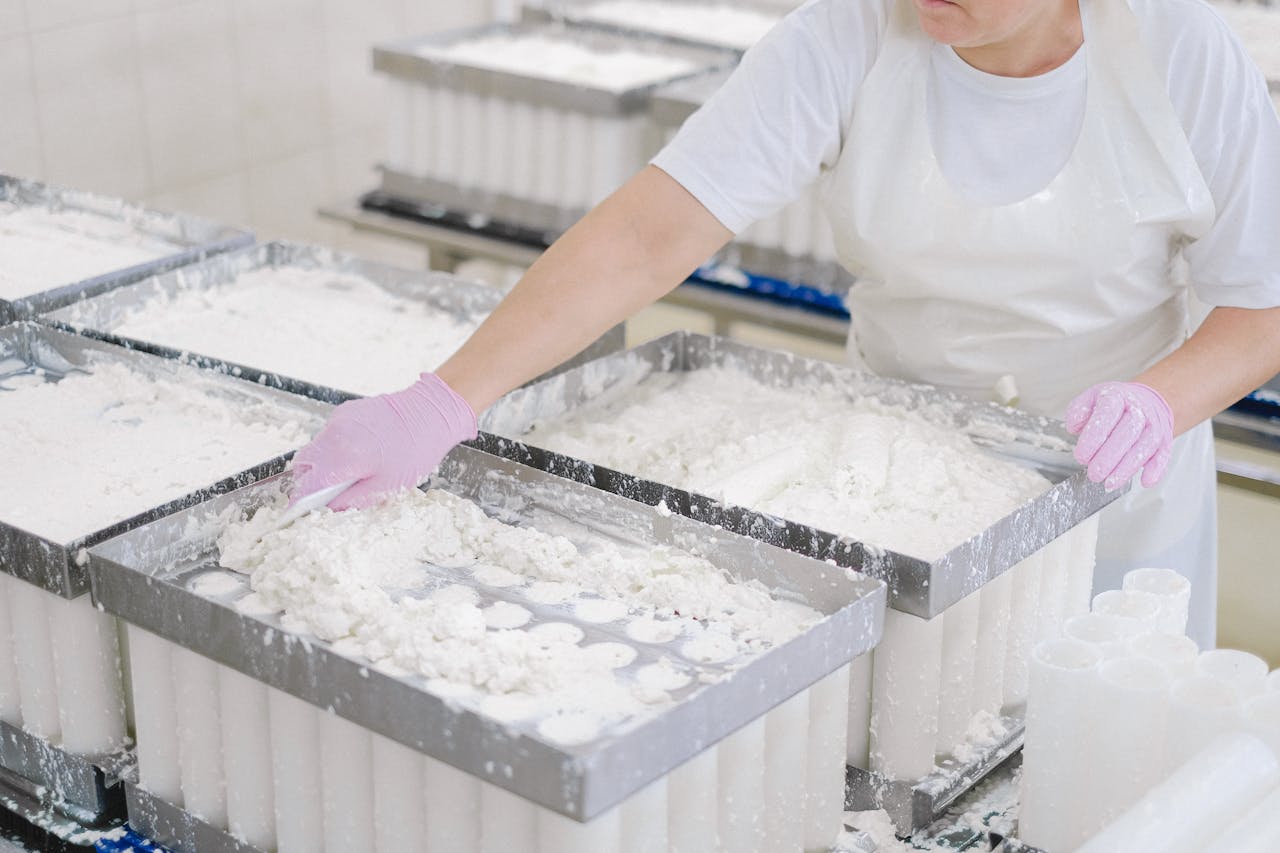 The Art of Drawing Readers In: Your attractive post title goes here Worker in protective gear handling cheese curds in an industrial dairy setting.