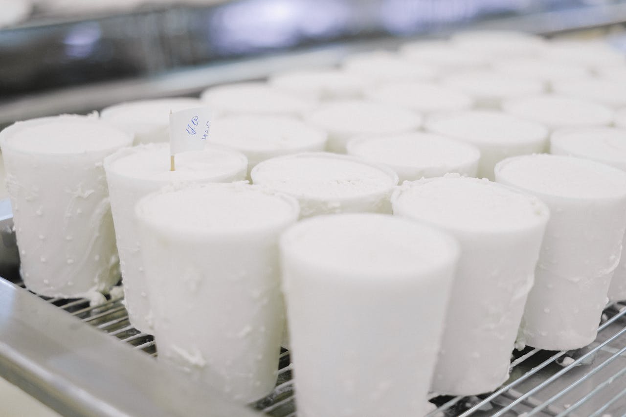 why-choose-us Cheese wheels curing in a dairy factory, showcasing industrial production.