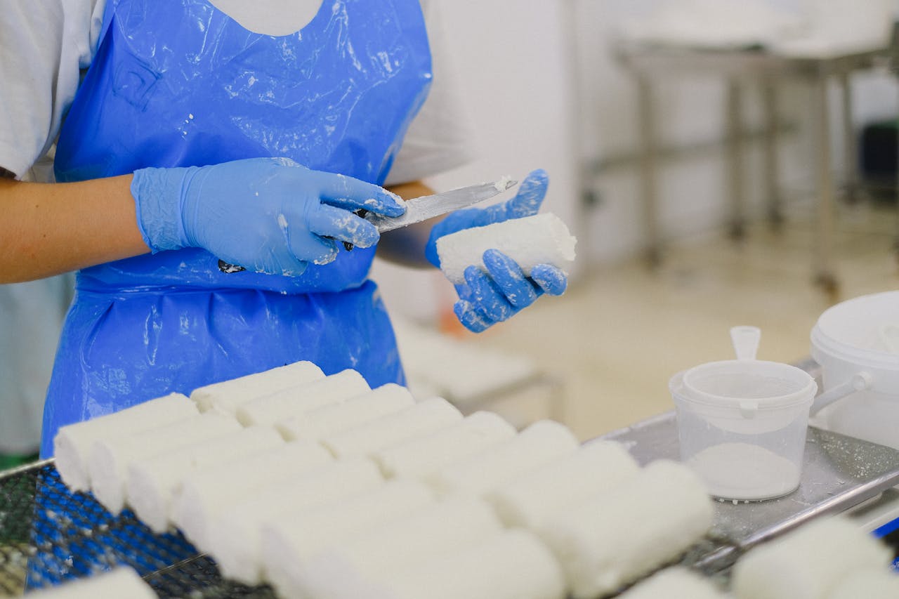 services-05 Worker processing cheese with gloves in a sterile dairy factory environment.