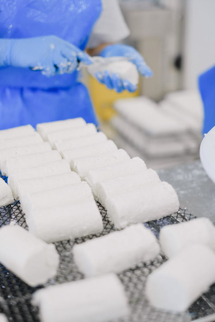 our-story Close-up of cheese being processed by workers in an industrial setting.