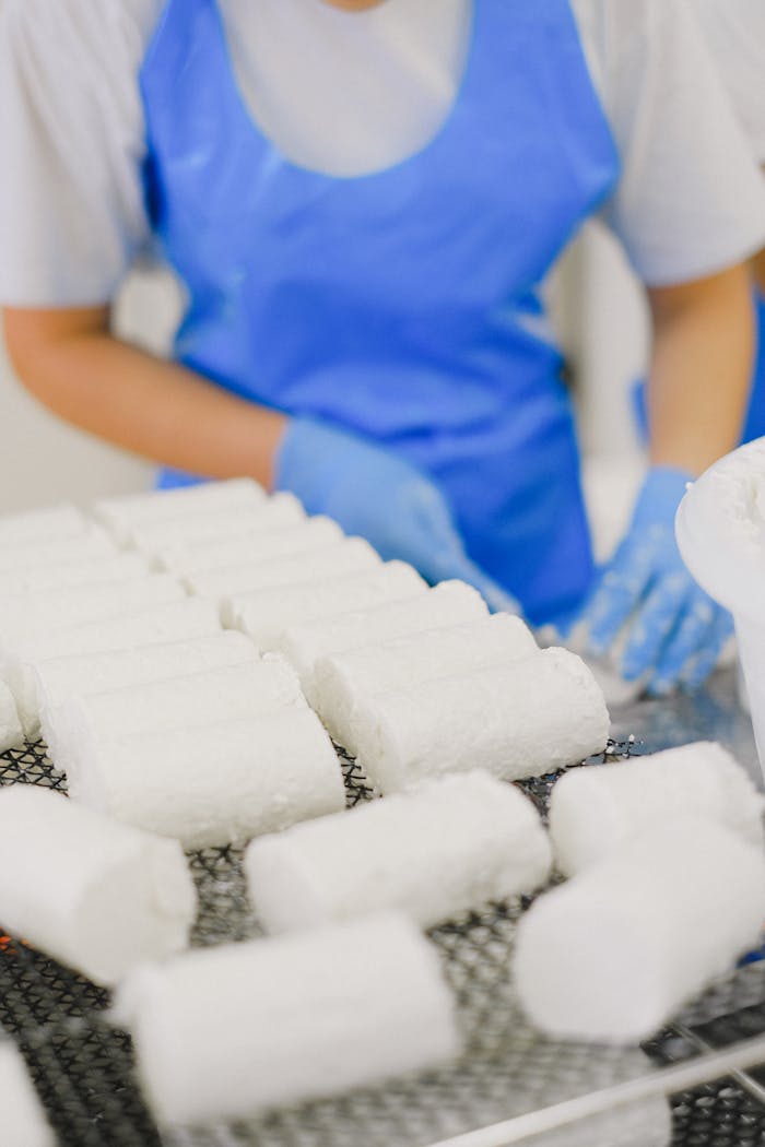 Crafting Captivating Headlines: Your awesome post title goes here Close-up of worker in protective gear handling cheese blocks on a production line.