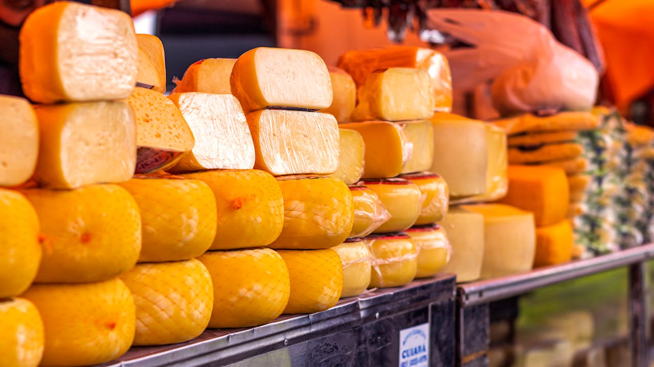 services-bg Close-up of various cheeses wrapped and displayed on a market shelf.